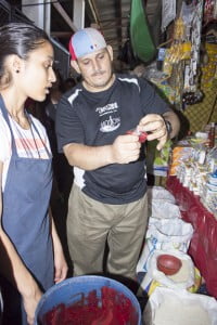 A vendor teaches Aashna how to bag ketchup.