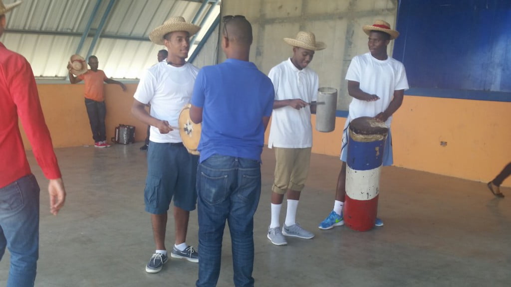 Robert, Rashid, and Malcom learning to play traditional Dominican instruments before they can dance with the women. 
