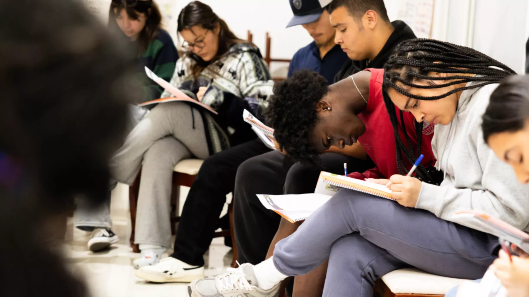 Group of students sitting in a circle and writing/reflecting in journals