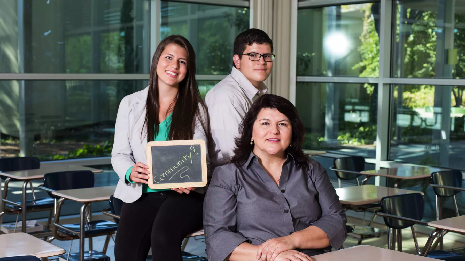 Three people posing for the camera in an empty classroom