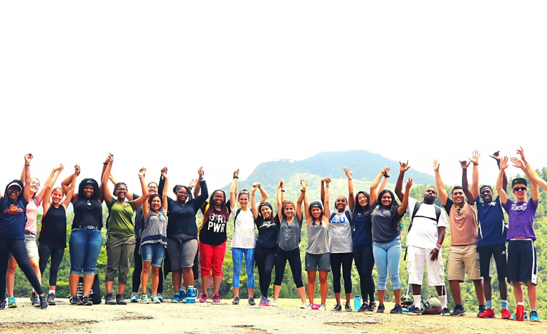 Group of students holding their hands up and smiling at the camera