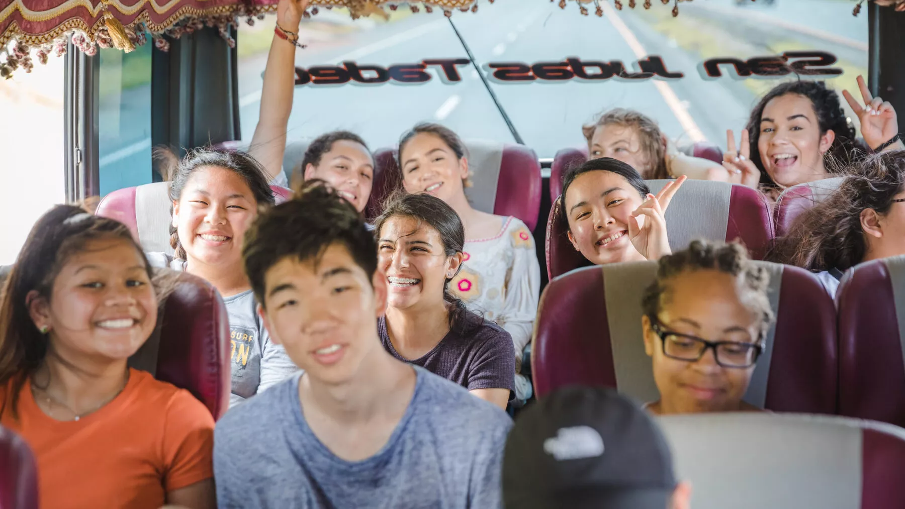 Candid picture of students on a bus traveling and smiling at the camera