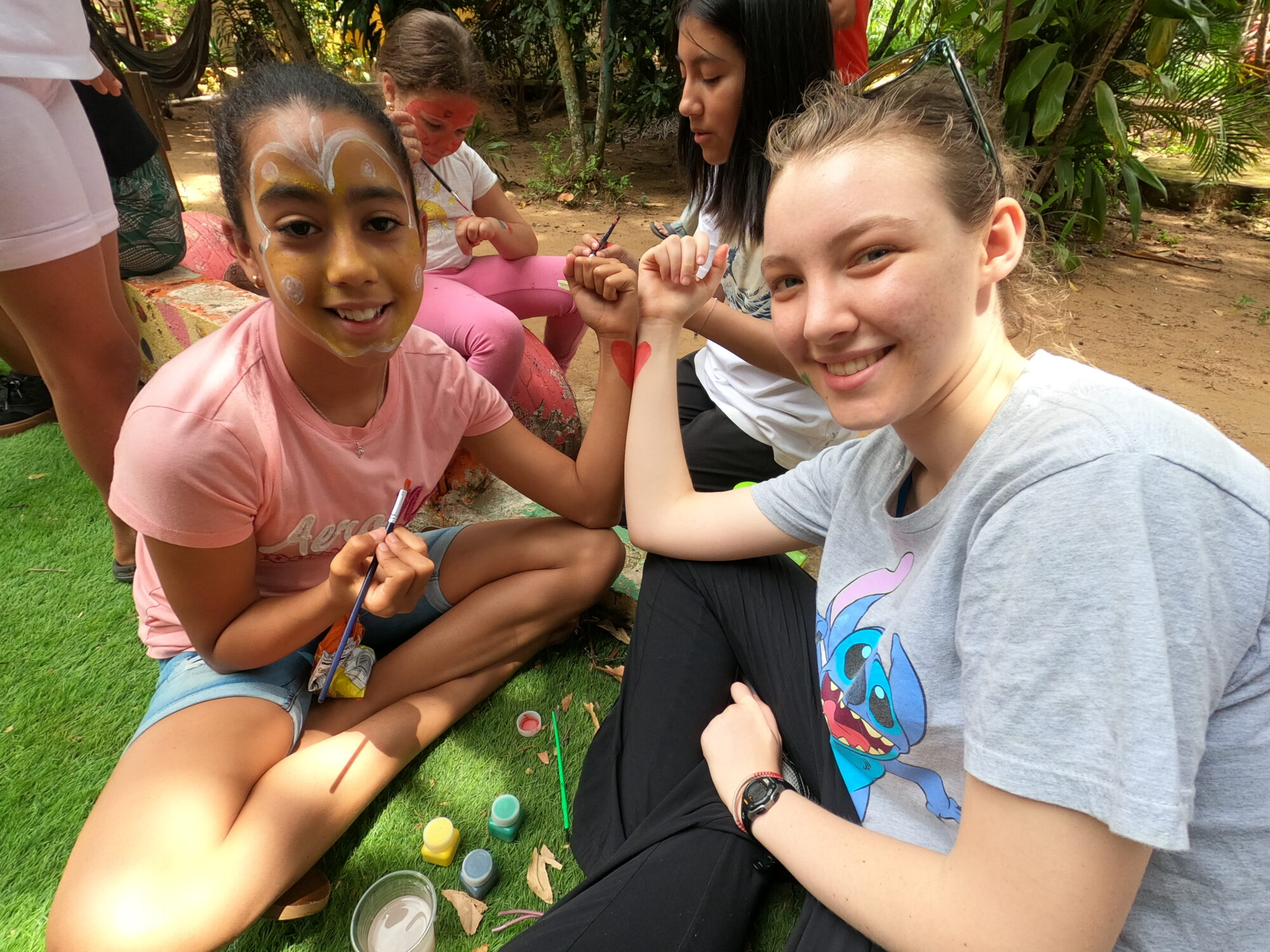 A Glimpser and child in face paint touch arms together, each arm supporting half a painted heart.